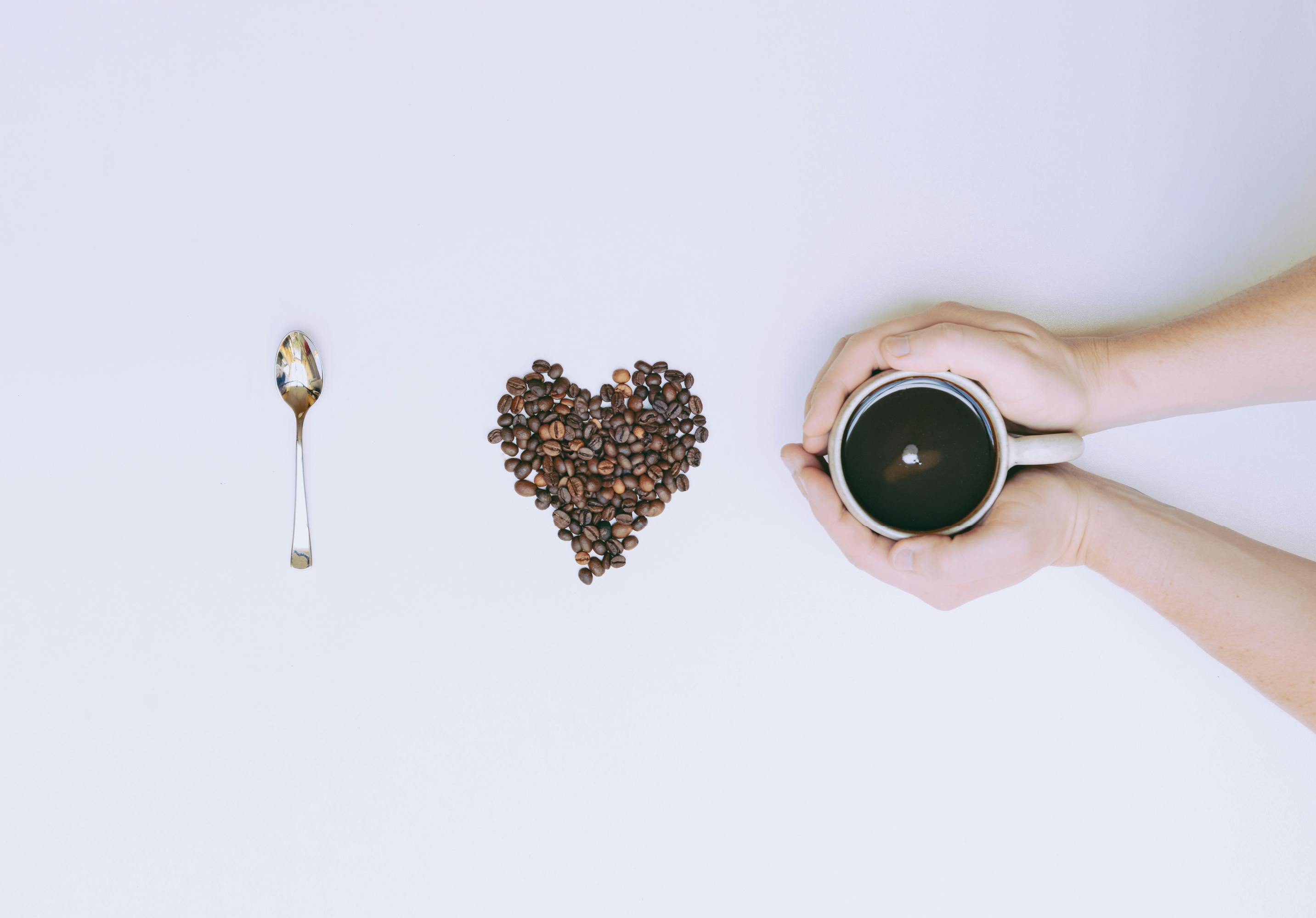 Frase 'i love coffee' representada con una cuchara, granos de café formando un corazón y una taza de café vista desde arriba